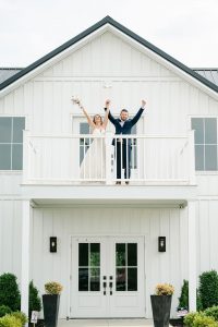 bride and groom with hands up on balcony