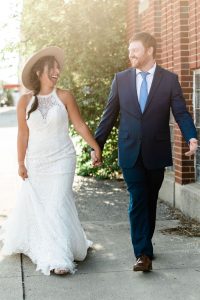 bride and groom holding hands and walking down sidewalk